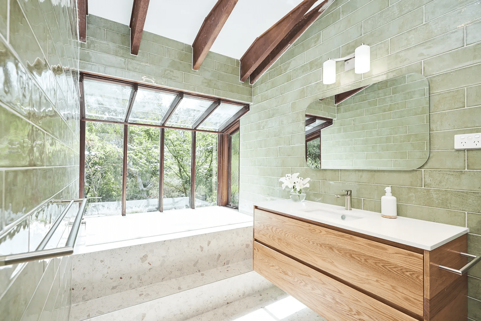A bathroom featuring green tile walls and wooden cabinets, creating a fresh and natural aesthetic.