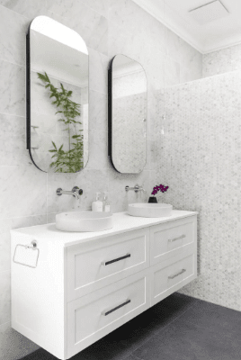 A modern bathroom with sleek white marble walls and a contrasting black and white tile floor design.