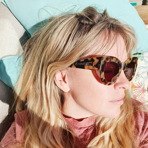 A woman wearing sunglasses reclines on a couch, embodying comfort and relaxation in a contemporary setting.