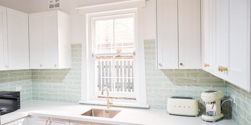 Stylish kitchen design with white cabinets complemented by green tile details.