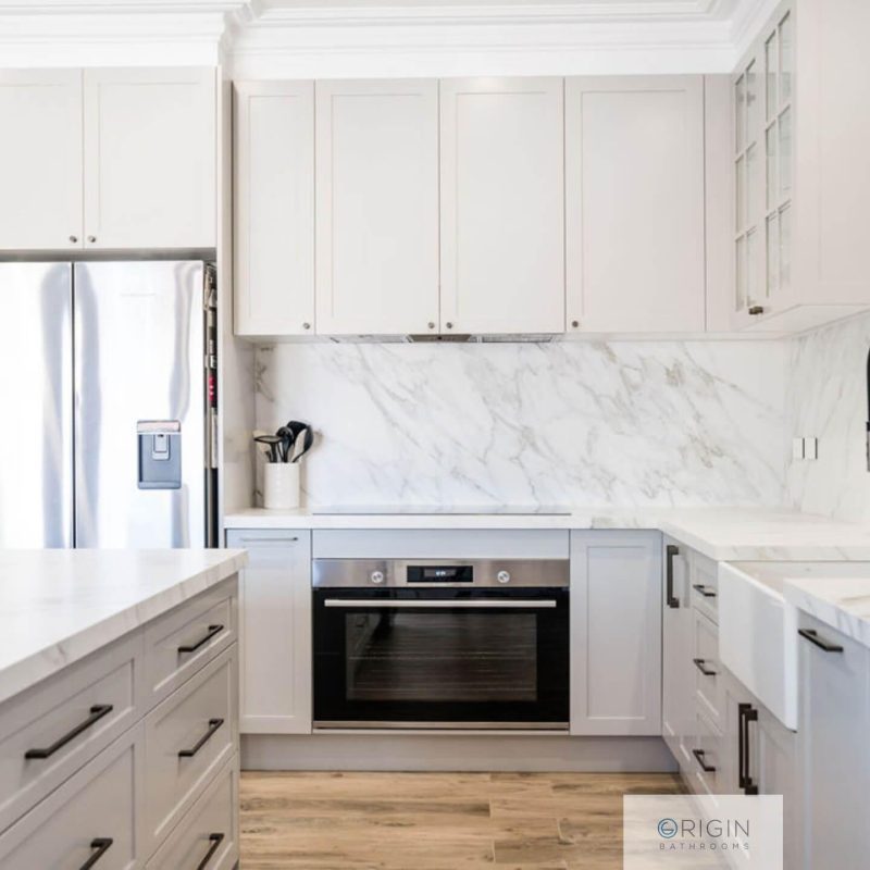 A stylish white kitchen showcasing polished marble countertops and ample natural light.