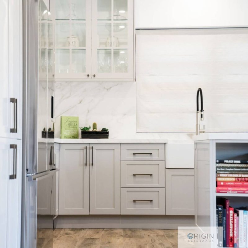 Bright kitchen with white cabinetry and a bookshelf displaying various cookbooks and kitchen decor.