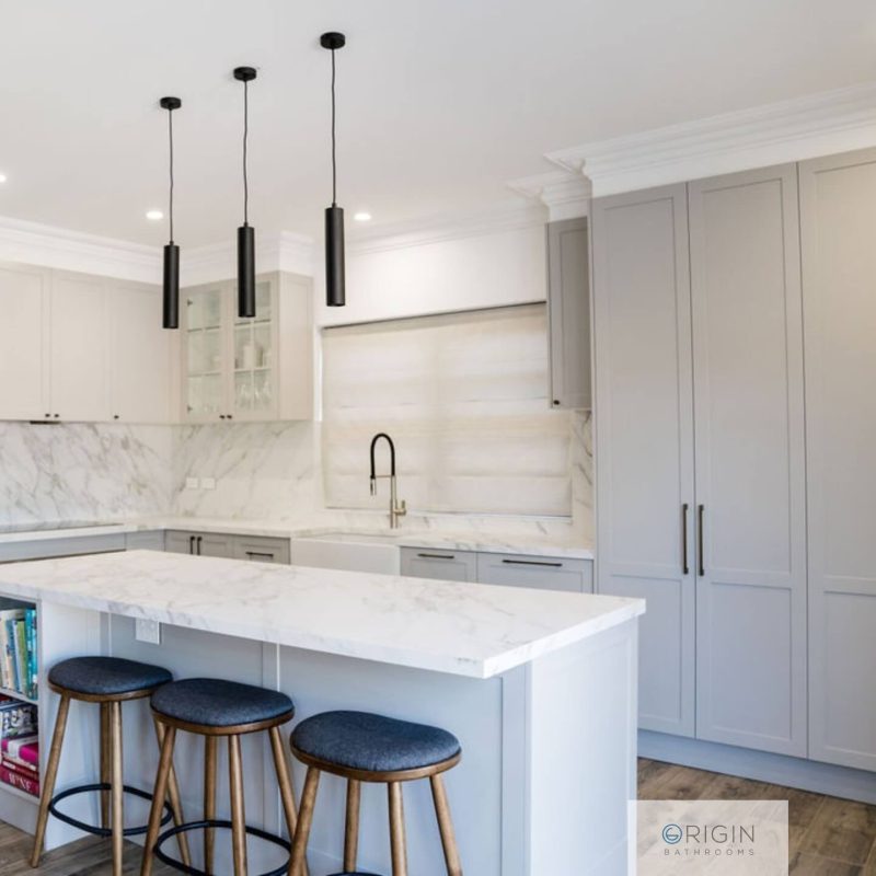 A clean, modern kitchen in white, highlighted by luxurious marble countertops and minimalist decor.
