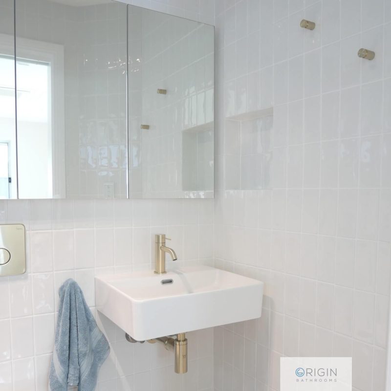 A modern bathroom adorned with white tiles and a simple sink, reflecting a fresh and uncluttered aesthetic.